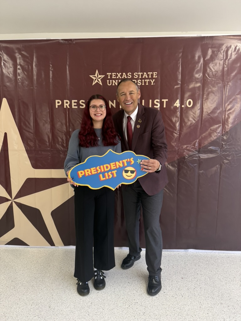 Two people pose together holding a blue 'President's List' sign in front of a Texas State University backdrop showing 'President's List 4.0'.