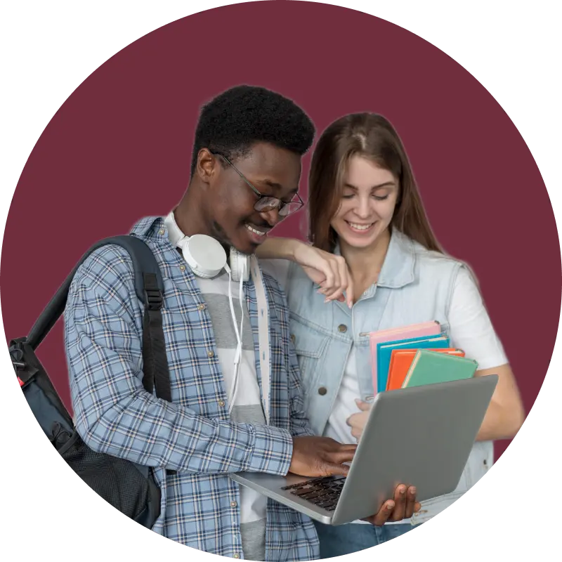 Two students studying together, one wearing headphones and pointing at a laptop screen.
